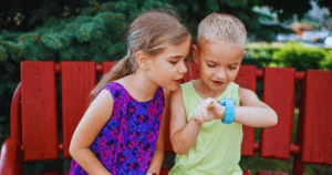 Egy kislány és egy kisfiú egymás mellett ülve nézik a kisfiú okosóráját