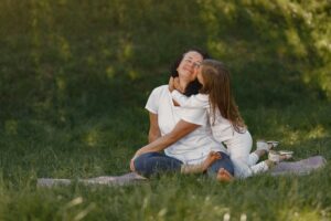 Egy kislány puszit ad az anyukájának egy réten