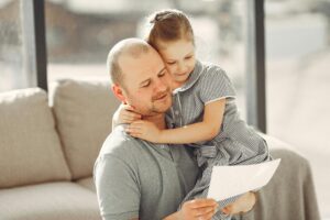 Apuka átöleli a lányát és együtt olvasnak egy papírlapot